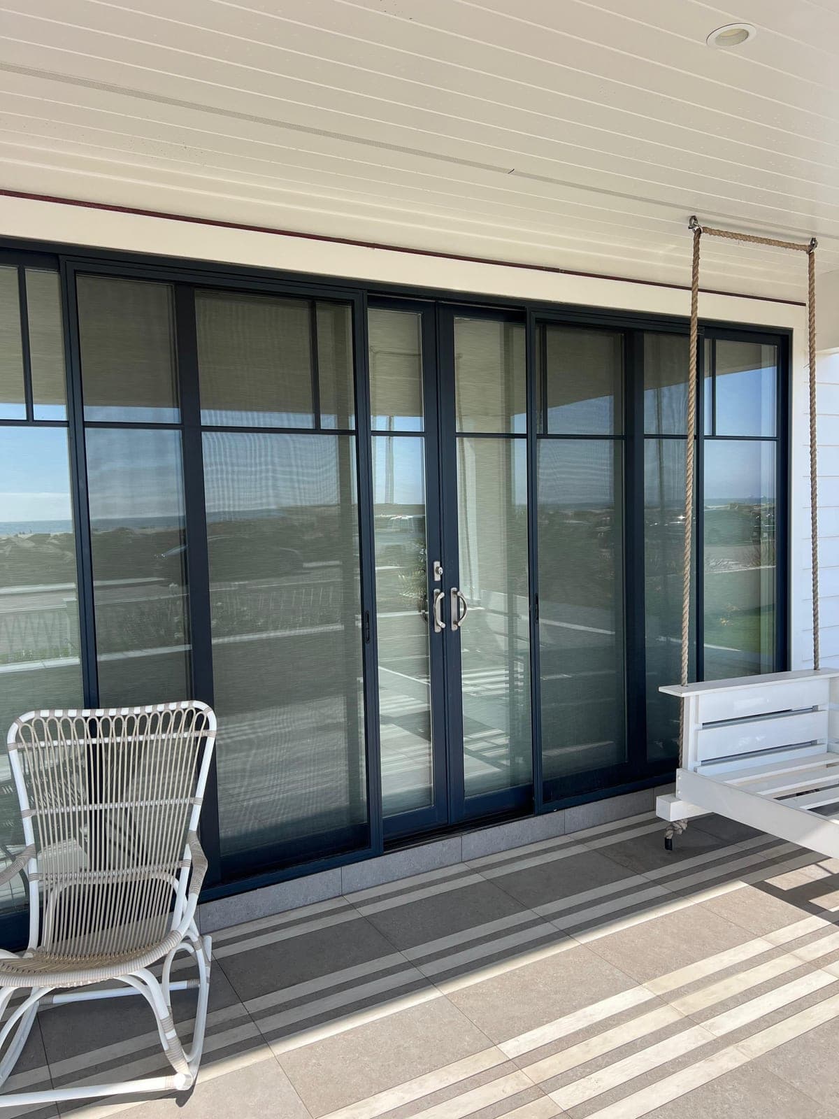 A porch wall of sliding glass doors with new, clear screens across every panel.