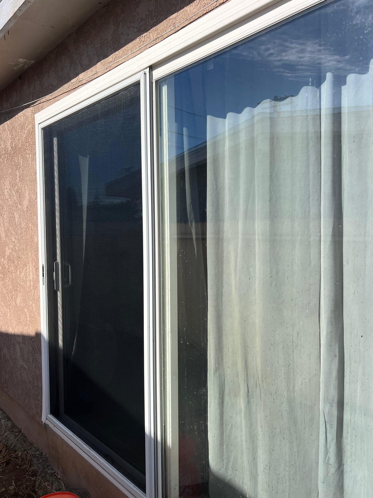 A sliding window with a fresh screen fitted in its white aluminum frame.