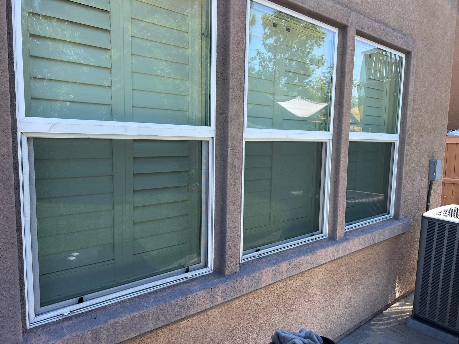 Three house windows side by side, each fitted with a new screen.