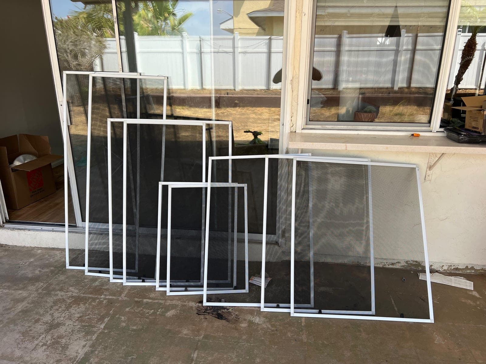 White-framed screens in several sizes leaning against the back of a house.