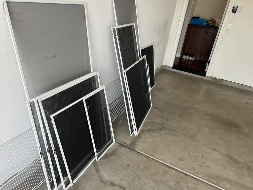 Custom-made window screens staged inside a clean garage, ready to be installed by Screenova Solutions.
